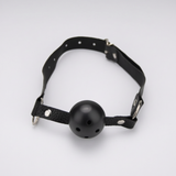 Black leather gag collar with a matte black silicone ball mouthpiece and silver metal hardware, photographed on a clean light gray background.